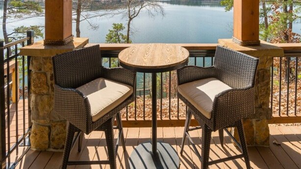 A balcony with wicker chairs and a table, overlooking a lake. - Dreamcatcher On Lake Coronado (Hot Springs Village)
