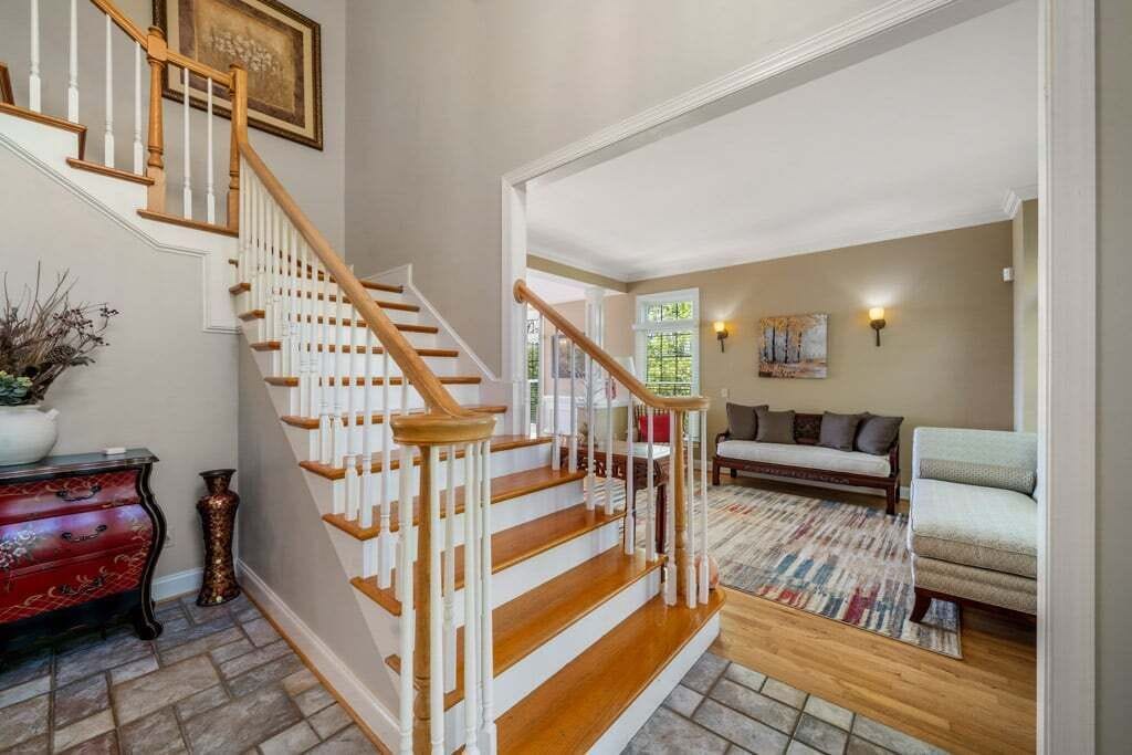 A staircase with white railings and wooden steps leading to a living room with a sofa and a rug.