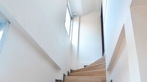 Una escalera de madera con paredes blancas y un tragaluz.