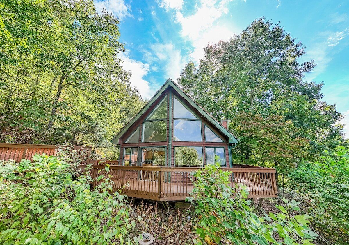 Eine Holzhütte mit Glasfront, umgeben von dichtem Wald.