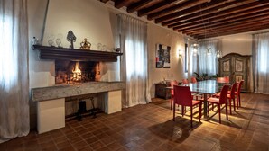 A dining area with a fireplace, red chairs, and a table.