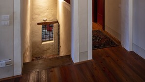 A hallway with wooden flooring, white walls, and an arched doorway leading to another room.