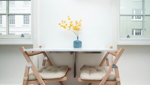 A room with a white table and two wooden chairs with cushioned seats. - Flat 1 Greek Street Apartments

 (London)