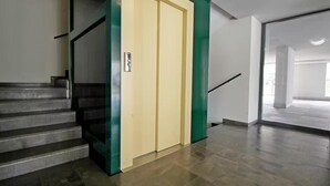 A modern interior with a staircase leading to a landing, a glass elevator, and a spacious hallway with a polished floor. - Stunning 1-bed Apartment in Verona (Verona)