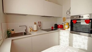 A modern kitchen with white cabinetry, a stainless steel sink, a red toaster, and a built-in oven. - Stunning 1-bed Apartment in Verona (Verona)