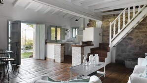 A spacious living area with a dining set, a kitchen with a stone wall, and a staircase. - Abejas 2 El Vergel de Chilla (Candeleda)