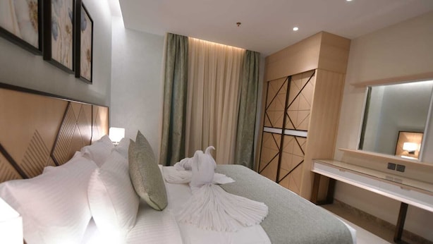 Une chambre d’hôtel moderne avec un grand lit, une table de chevet, un miroir et une vue sur la ville.