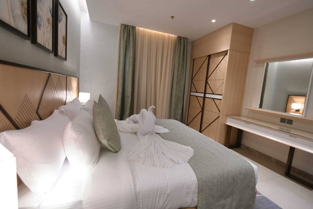 Une chambre d’hôtel moderne avec un grand lit, une table de chevet, un miroir et une vue sur la ville.