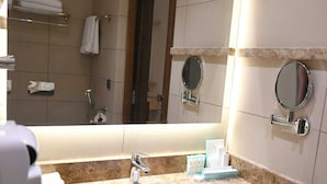 Une salle de bain équipée d’un lavabo, d’un miroir, d’un porte-serviettes et d’un sèche-cheveux.