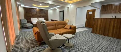 A modern hotel room with a sofa, armchair, and a small table.