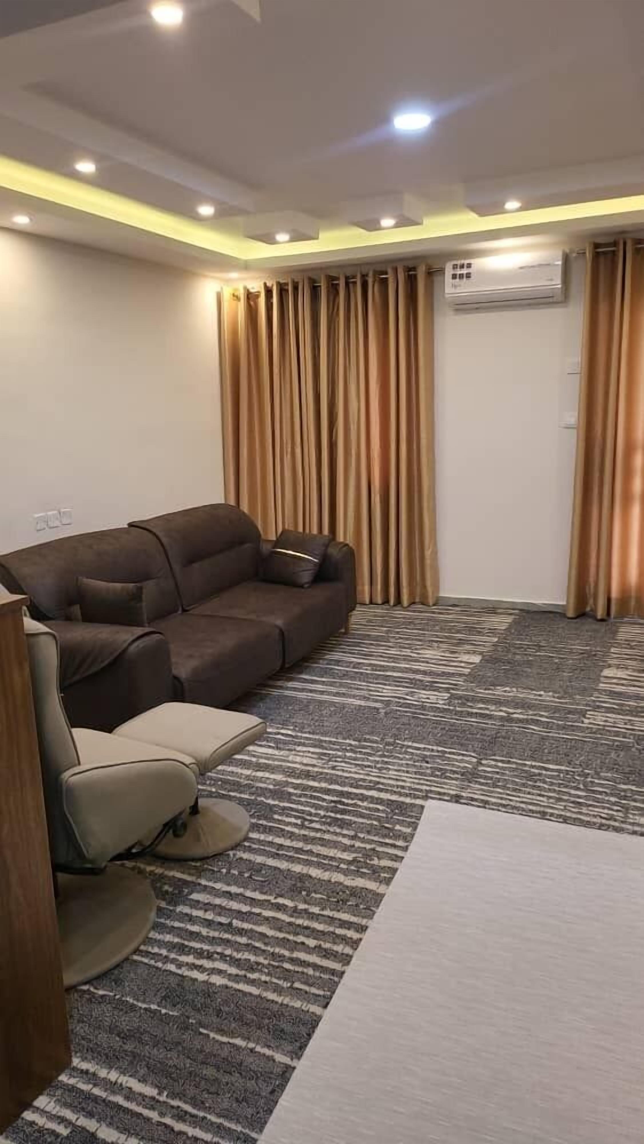 A modern living room with a sofa, a chair, and a patterned carpet.