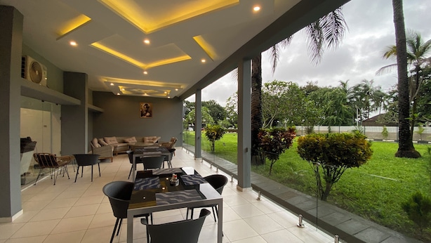 A modern outdoor dining area with a glass partition, a sofa, and a table set for dining. - LIA Hotel (Lungi)