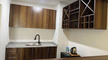 Una cucina con mobili in legno, un piano di lavoro in granito, un lavello in acciaio inossidabile e un bollitore su un tavolino.