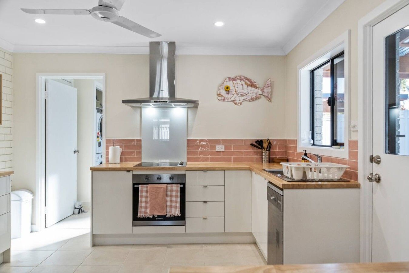 A modern kitchen with a central island, stainless steel range hood, and a window with a view.
