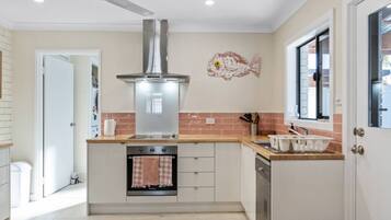 A modern kitchen with a central island, stainless steel range hood, and a window with a view.