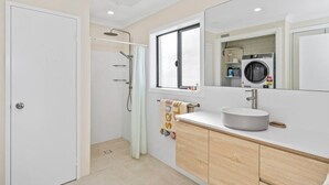 A modern bathroom with a shower, a sink, and a mirror. - Sandy Shores Getaway (Mandurah)