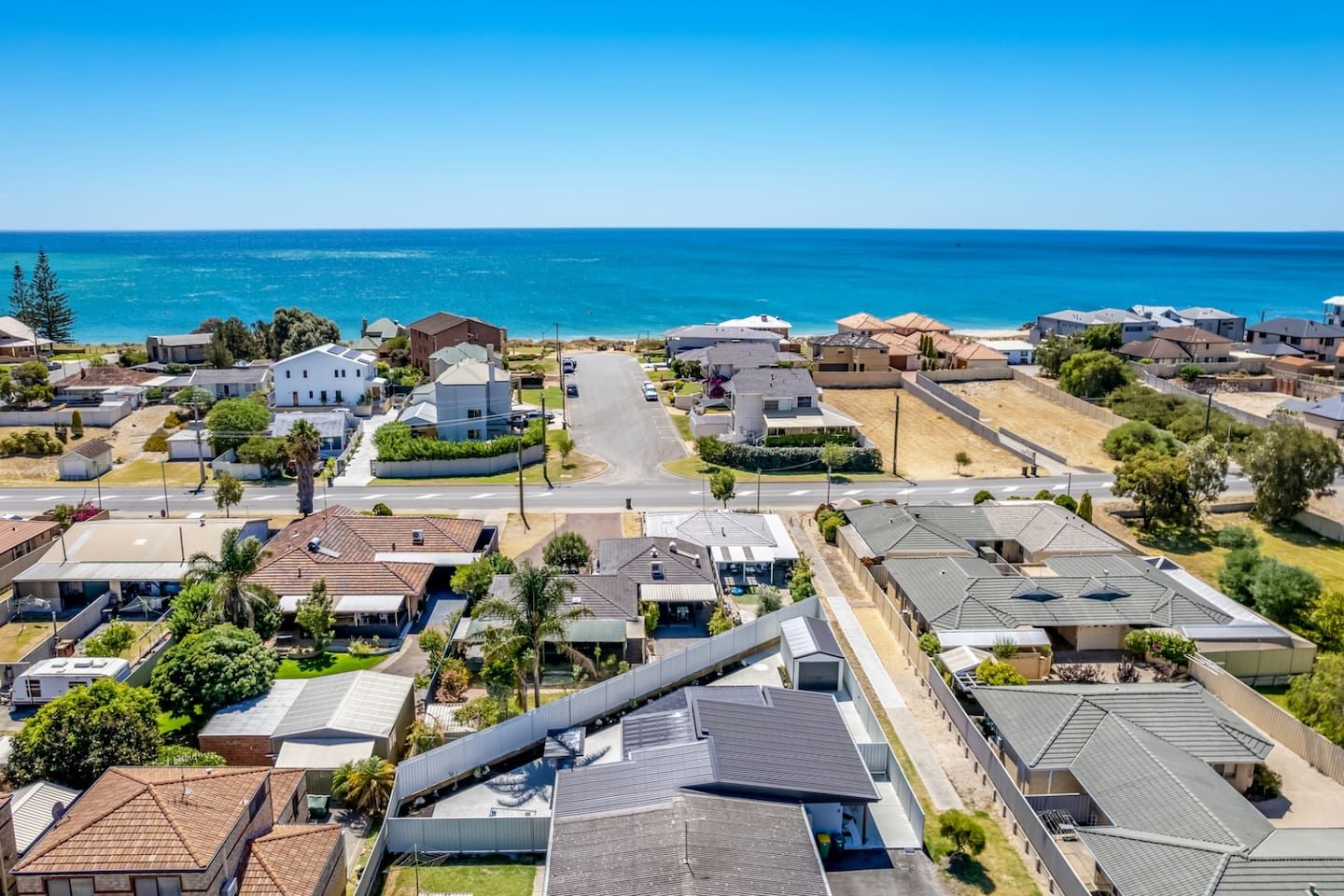 A residential area with houses, a road, and a view of the ocean.