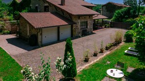 A stone house with a tiled roof, a garage, and a paved driveway. - The Basque Experience by Fidalsa (Otxandio)