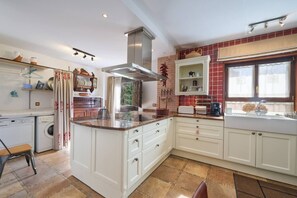 A kitchen with a central island, white cabinetry, a built-in oven, and a window with curtains.