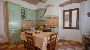 A dining area with a table set for four, surrounded by wooden chairs. - CasaMatta2 Apartment in the heart of the medieval village of Giglio Castello. (Giglio Castello)