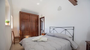 A bedroom with a bed, a wooden wardrobe, a chair, a bedside table, and a potted plant. - CasaMatta2 Apartment in the heart of the medieval village of Giglio Castello. (Giglio Castello)