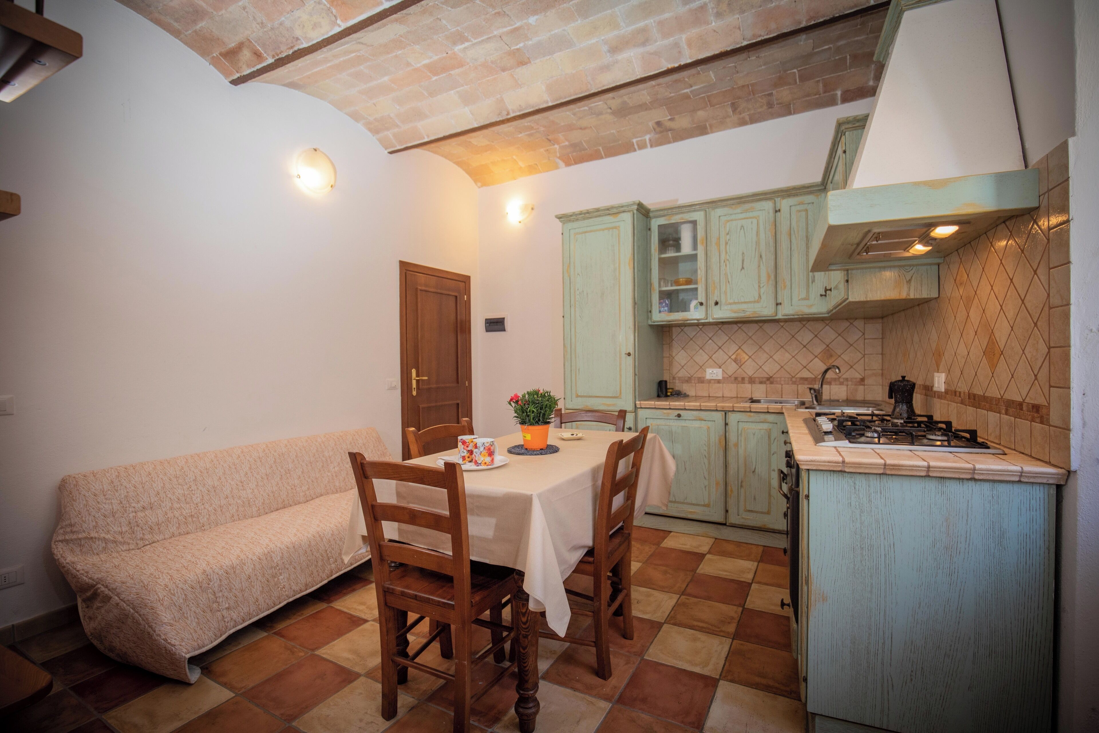 Una cucina accogliente con un tavolo da pranzo, sedie di legno, un divano e un piano cottura a gas.