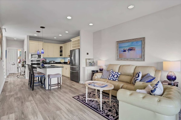 A modern living room with a beige sofa, a coffee table, and a dining area with a bar.