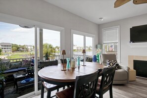 A spacious living room with a large window, a round dining table, and a comfortable seating area.