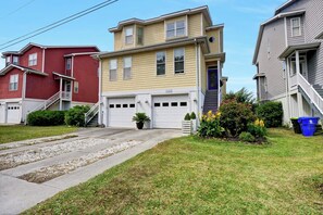 A two-story house with a garage, a front porch, and a small garden.