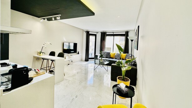 A modern living room with a sofa, a coffee table, and a TV. - StayInn Maarif Downtown (Casablanca)