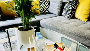 A modern living room with a glass coffee table, a potted plant, and a tray with water bottles and glasses. - StayInn Maarif Downtown (Casablanca)