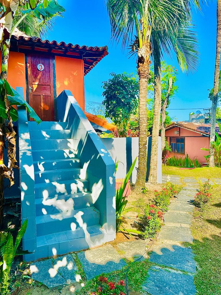 Zona residencial con una escalera que lleva a una casa, rodeada de palmeras y un jardín.