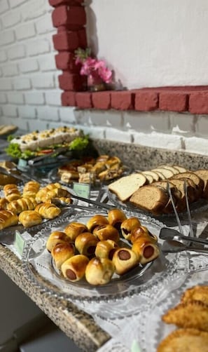 A buffet with various food items including bread, pastries, and a selection of vegetables.