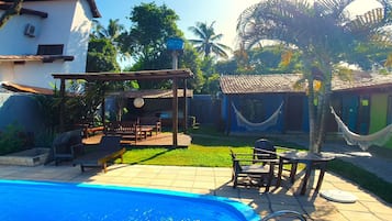 Una piscina al aire libre, sombrillas, sillones reclinables de piscina
