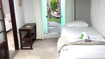 Um quarto pequeno e bem iluminado, com duas camas, uma escrivaninha de madeira e uma janela com cortinas.