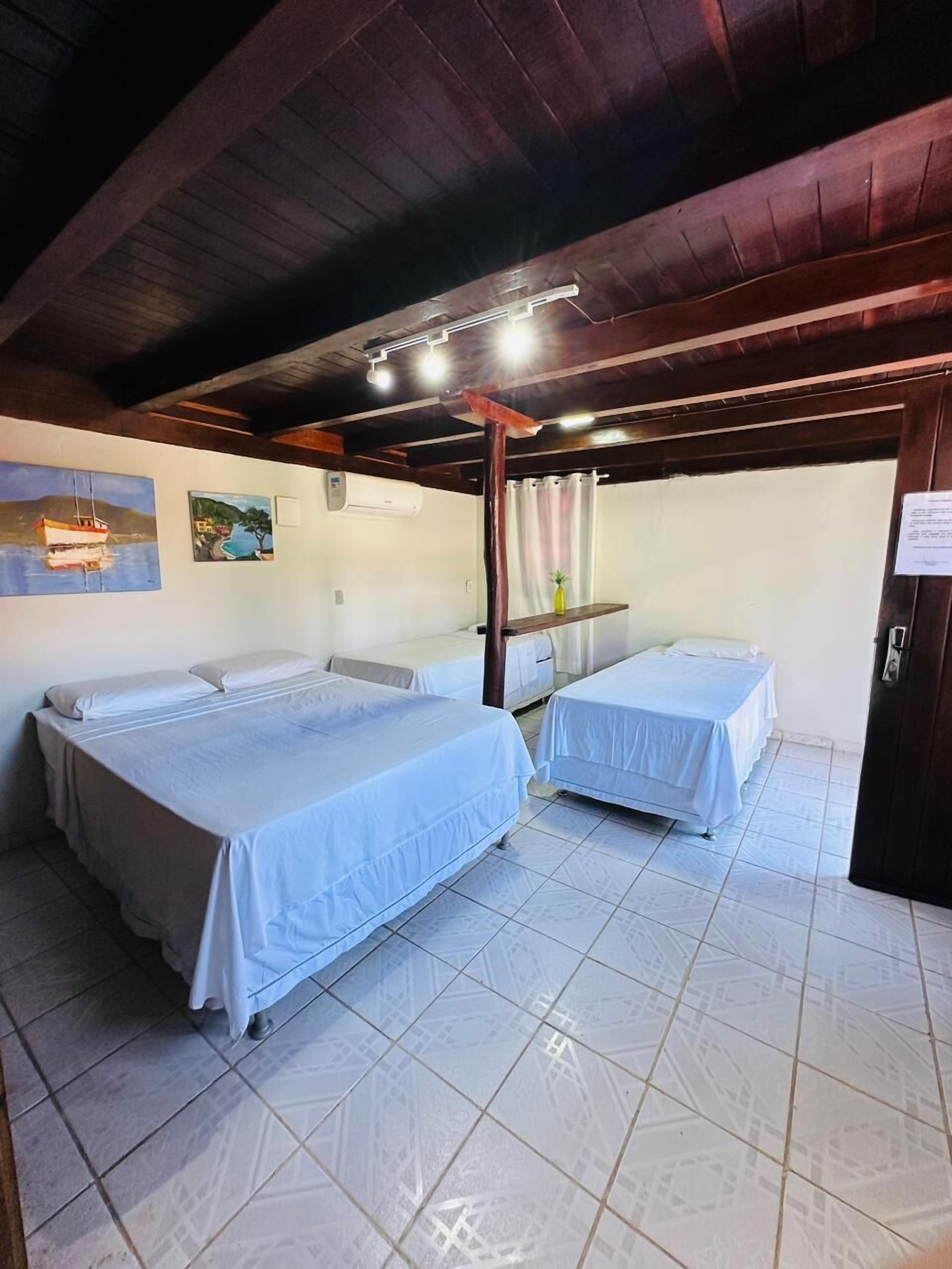 A room with two beds, a wooden ceiling, and artwork on the walls.