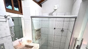 A bathroom with a glass-enclosed shower, a marble sink, and a tiled floor. - Pousada Tropicália (Porto Seguro)