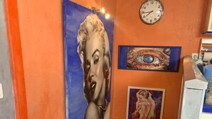 A staircase with a blue and orange wall, a clock, and a framed painting of an eye. - Appartement de Luxe au Cœur D'aix-en-provence (Aix-en-Provence)
