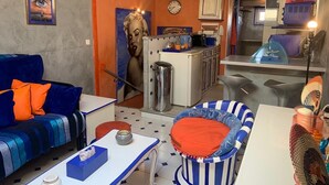 A compact living space with a kitchenette, a sofa, a striped chair, and a small table with a tissue box. - Appartement de Luxe au Cœur D'aix-en-provence (Aix-en-Provence)