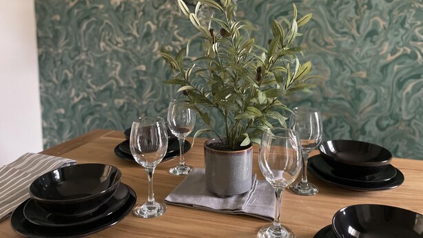 A dining table set with black plates, clear wine glasses, and a potted plant. - Convenient 3 bd House Salford 7 Guests (Salford)