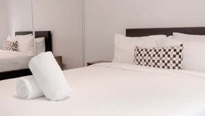 A neatly made bed with white linens, a dark headboard, and patterned pillows. - St Kilda Rd Gem | Prime Spot (Melbourne)