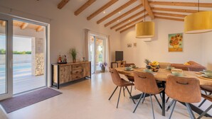 Un vaste espace dédié à la salle à manger, avec une table et des chaises en bois, une grande fenêtre et une vue sur une piscine.