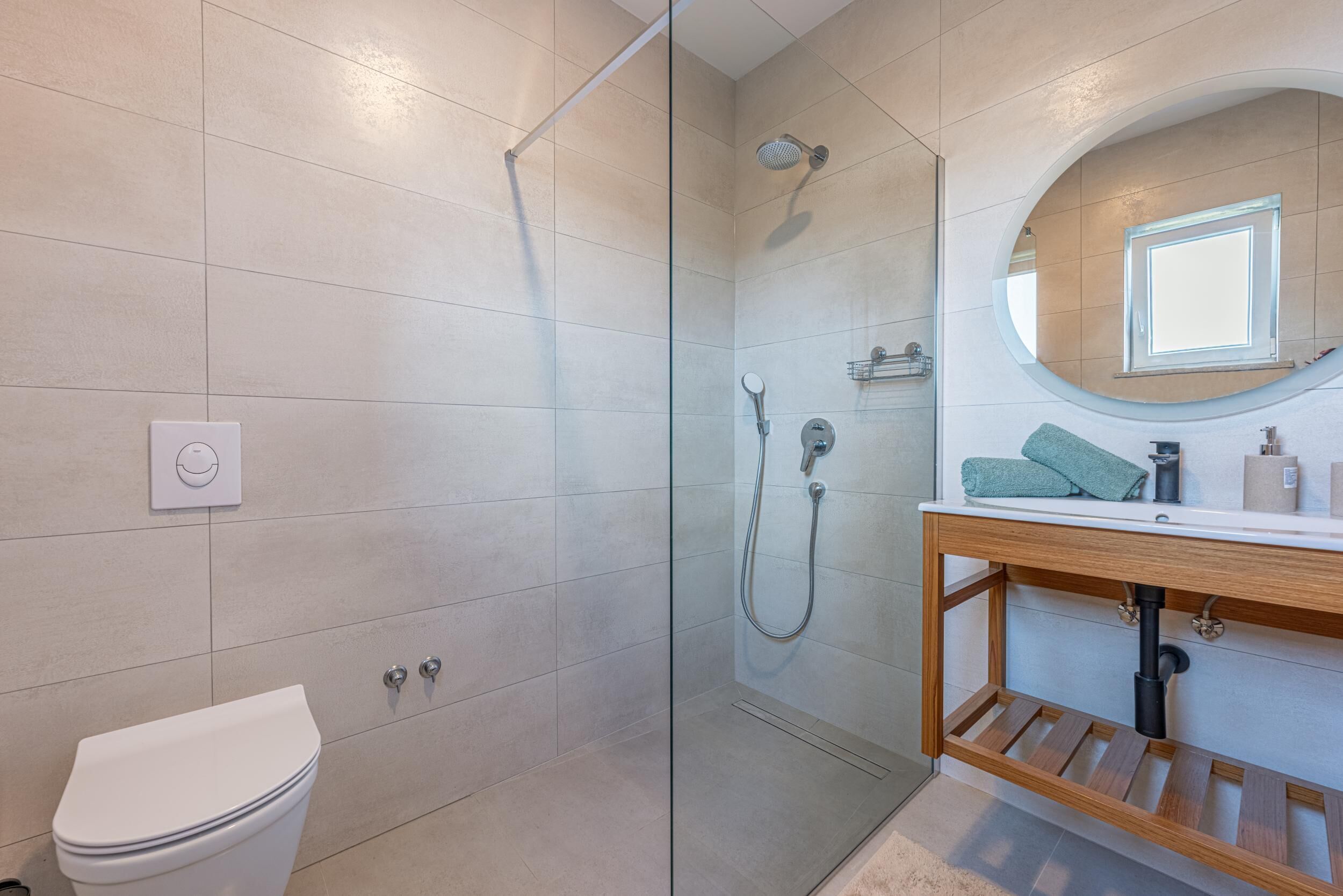 A modern bathroom with a glass-enclosed shower, a white toilet, and a wooden vanity with a mirror.