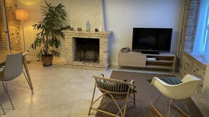 Un soggiorno moderno con camino in pietra, una TV a schermo piatto e due poltrone a dondolo.