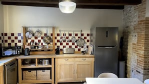 Una cucina compatta con mobili in legno, un frigorifero in acciaio inossidabile e un portaspezie a sospensione.
