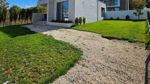 A modern two-story house with a gravel driveway and a well-maintained lawn. - Villa Tiffany (Telavi)
