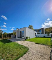 A modern two-story house with a gravel driveway and a well-maintained lawn.