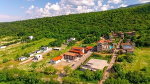 A hillside village with traditional houses, a central building with a red roof, and a paved road. - Villa Tiffany (Telavi)