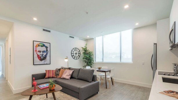 Ein modernes Wohnzimmer mit Sofa, Couchtisch und einem Essbereich mit Tisch und Stühlen.