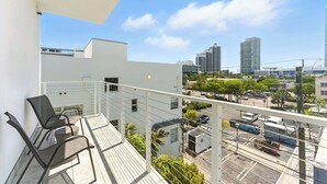 Ein Balkon mit zwei Stühlen und Blick auf eine Skyline mit hohen Gebäuden.